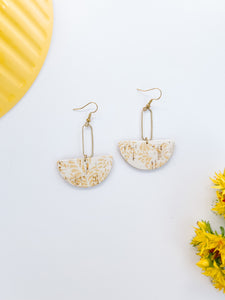 white cork half moon shape earrings with a soft yellow floral print and brass accents