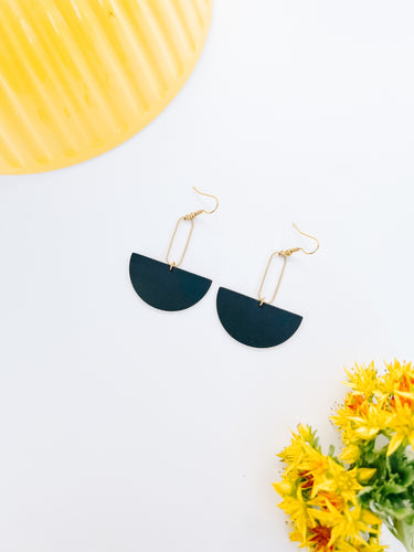black leather half moon dangly earrings hanging from a small brass oval accent