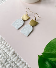 Load image into Gallery viewer, white leather earrings with a brass accent on top
