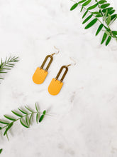 Load image into Gallery viewer, mustard yellow leather earrings in a d shape with horseshoe brass accent
