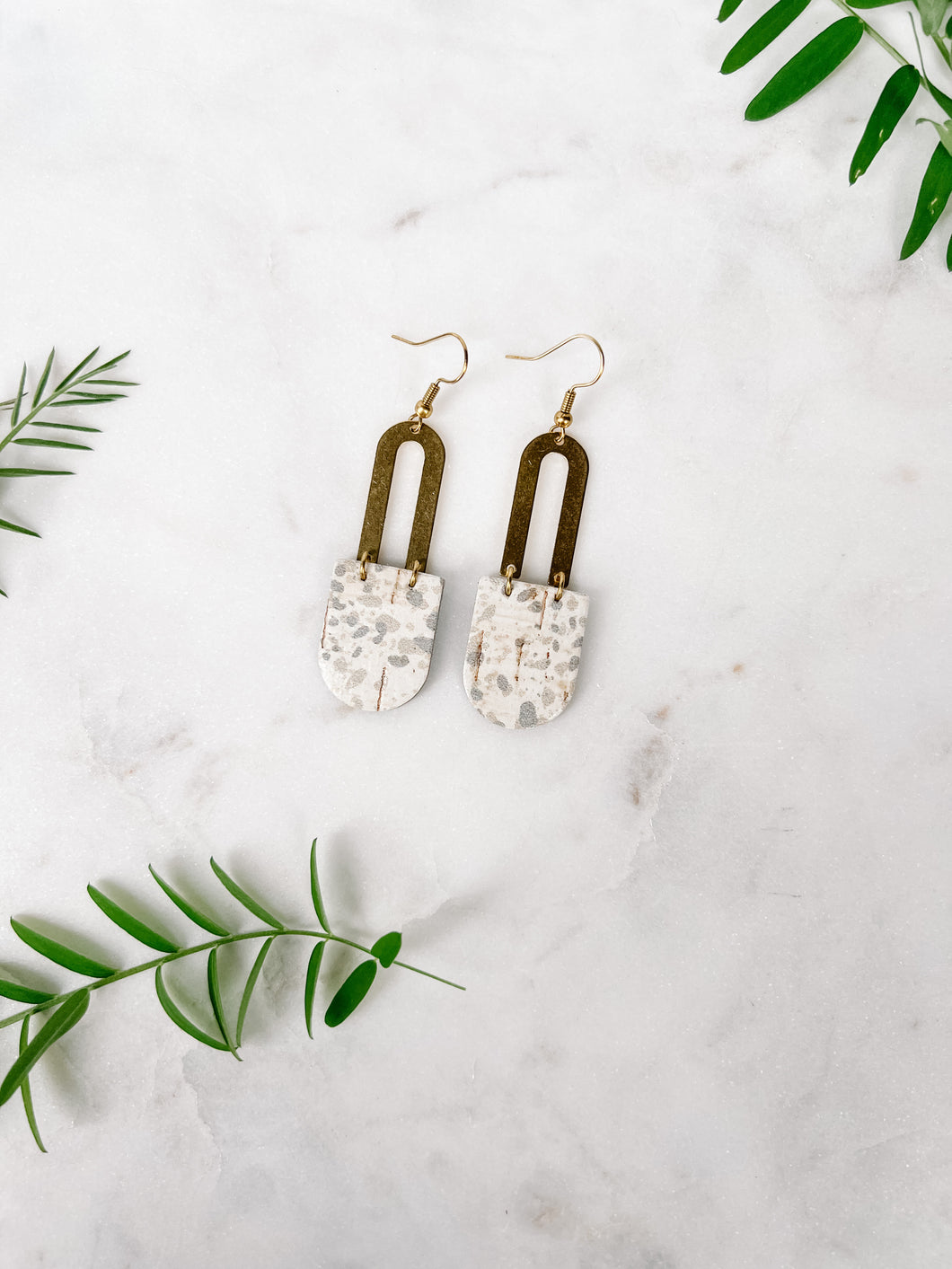 speckled white and grey leather earrings with a brass horseshoe accent